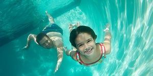 Father and daughter swimming, underwater view- Clearwater Pools